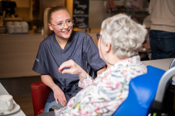 Medewerker in gesprek met bewoner in brasserie