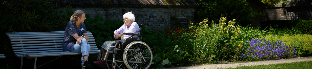 Medewerker in gesprek met bewoner in de tuin van een vestiging