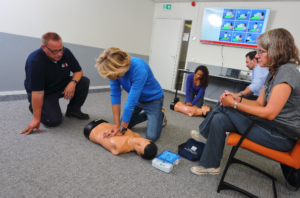 Een man die EHBO en BHV training geeft aan een groep mensen. Echte situaties worden naageboost. 