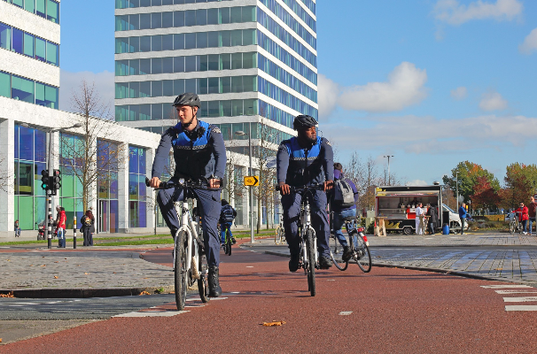 Twee handhavers op de fiets. Zij controleren de buurt en bewaken de veiligheid en orde. 